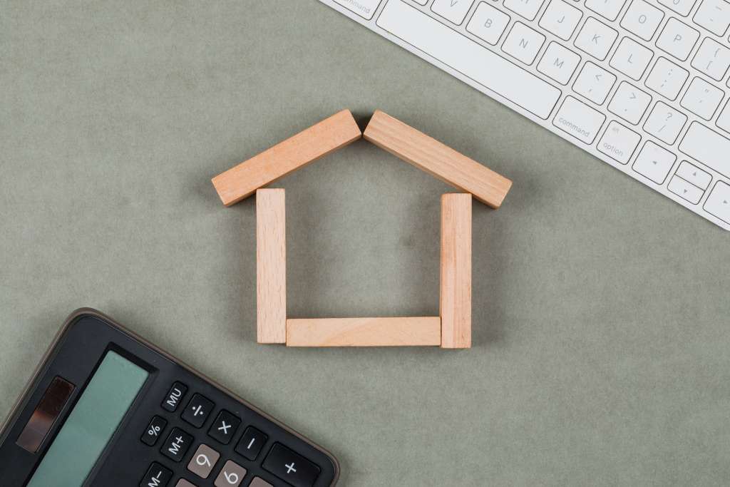 real estate concept with wooden blocks, calculator, keyboard on grey background flat lay.